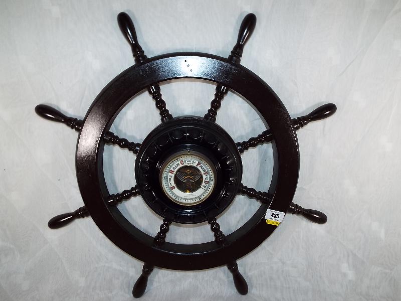 A wall mounted aneroid barometer in the form of a ships wheel, white enamel dial with open centre