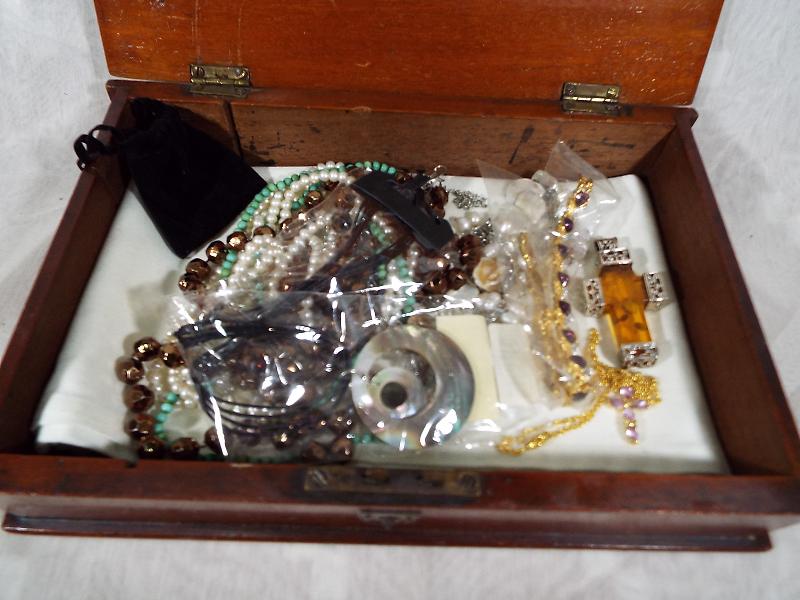 A mahogany box with opening hinge lid containing a quantity of costume jewellery to include a large - Image 2 of 3