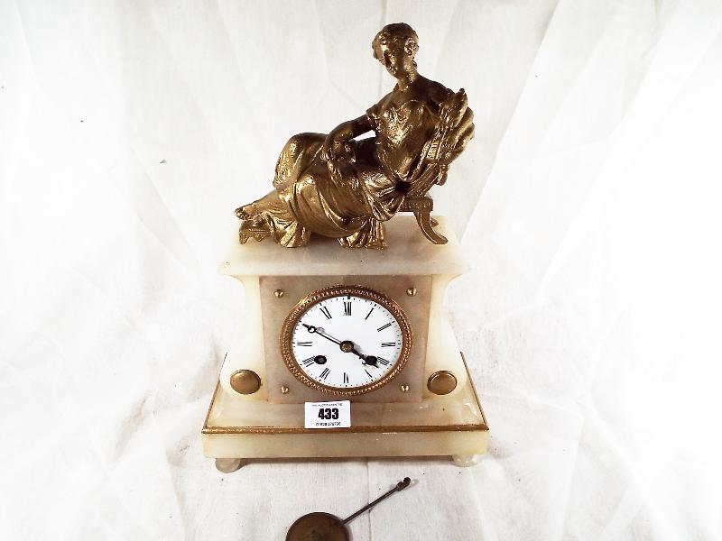 An alabaster mantle clock with relief decoration of a reclining lady, with bell striking and