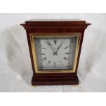 A good mahogany mantel clock by Comitti of London, square white dial with brass bezel, on brass bun