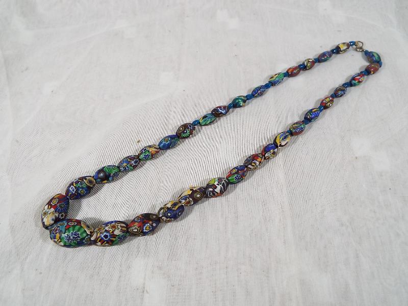 A heavy single strand beaded necklace, decorated with an intertwined millefiori design,