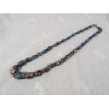 A heavy single strand beaded necklace, decorated with an intertwined millefiori design,