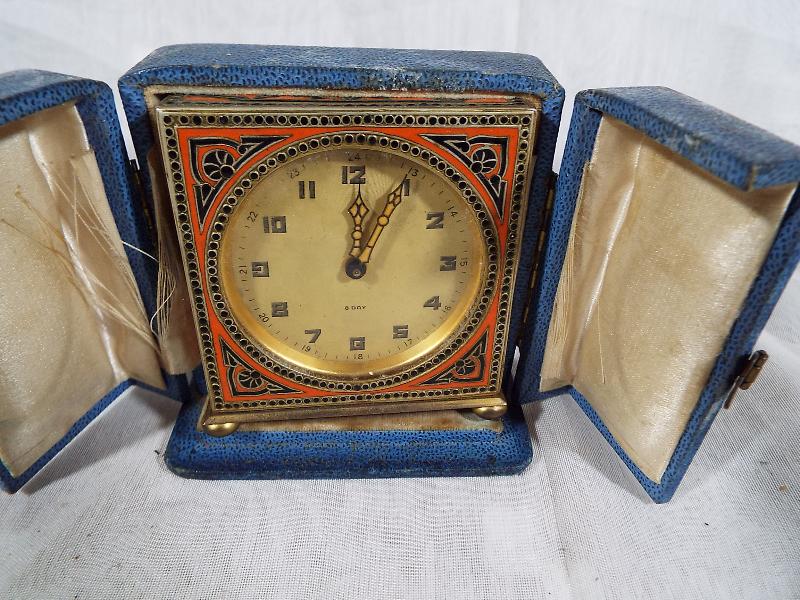 A desk timepiece, the brass case having black and orange enamelling, champagne dial marked 8 day,