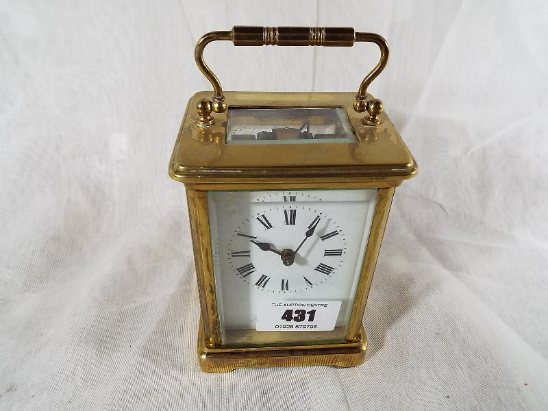 A French brass and glass panel carriage clock , Roman numerals on a white dial, with lever