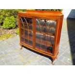 A mahogany bow-fronted display cabinet with astral glazed doors, the supports terminating in ball