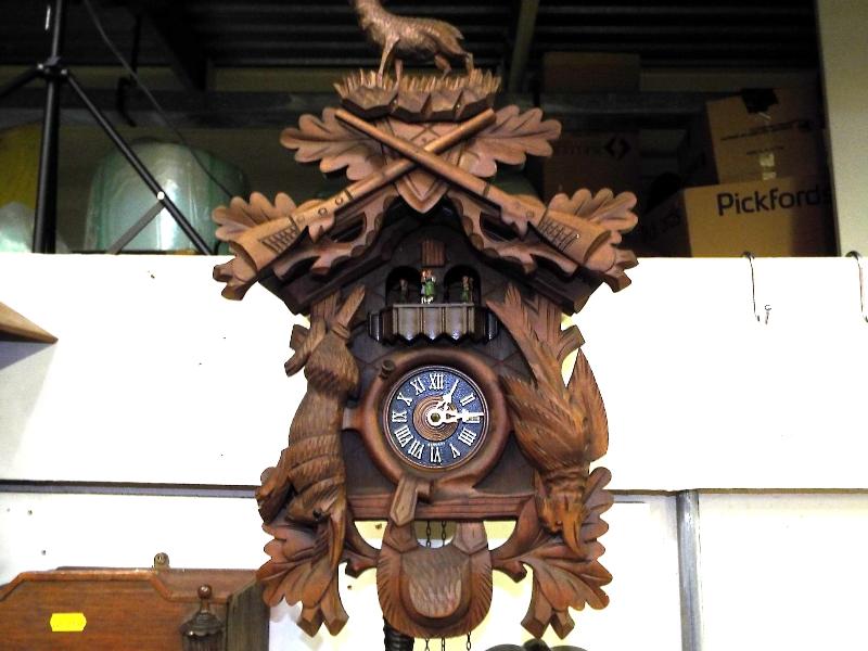 A decorative wall mounted cuckoo clock, two pine cone weights, carved animals to case and top