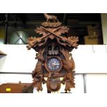 A decorative wall mounted cuckoo clock, two pine cone weights, carved animals to case and top