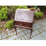 An early to mid 20th century small mahogany bureau with slope front opening to reveal a fitted