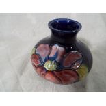 A Moorcroft pottery small swat vase decorated with Clematis on a cobalt blue ground, 7cm (h) Est