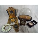 A good mixed lot of three small desk clocks, a brass compass, a small quantity of clock parts and