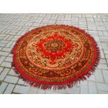 A circular red woven rug with tassels, 161cm (diam)