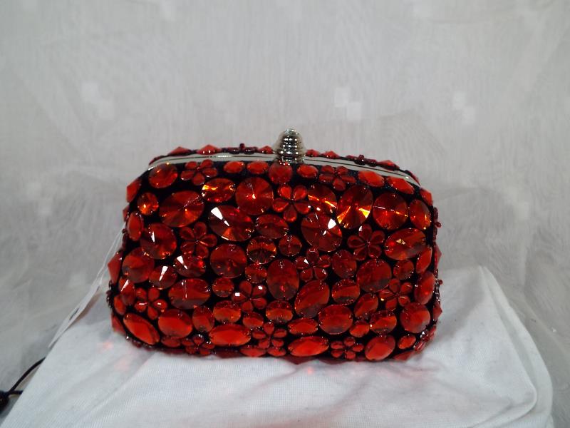 A lady's Butler & Wilson hard cased evening bag with gem stone decoration in red, spare strap and