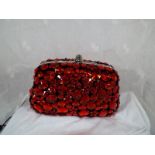 A lady's Butler & Wilson hard cased evening bag with gem stone decoration in red, spare strap and