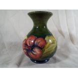 A Moorcroft Pottery vase with flared rim decorated with coral hibiscus on a green ground, paper