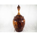 A large carved wooden lidded urn with depictions of native figures and animals, 58cm (h) x 30cm