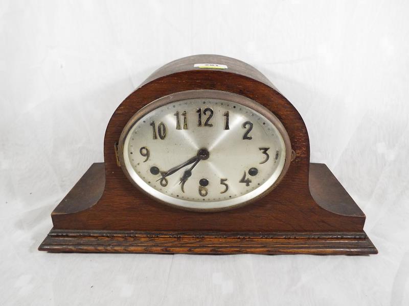 An oak cased Westminster chiming mantel clock, the oval silvered dial with applied brass numerals,