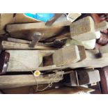 A collection of wooden hand tools, predominantly planes, a ceramic foot warmer and a vintage