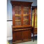 A mahogany cabinet with bookcase above, the glazed front doors opening to reveal a shelved