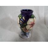 A Moorcroft pottery small balluster vase decorated in a floral design and signed to the base A.