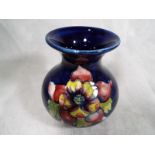 Moorcroft Pottery - A bulbous vase decorated in a floral design on a cobalt blue ground, paper
