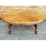 An oval topped walnut side table, 50 cm (h) x 105 cm (w) x 61 cm (d)