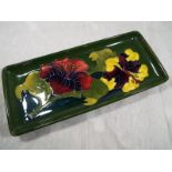 Moorcroft Pottery - A rectangular pen tray decorated with hibiscus on a green ground with paper