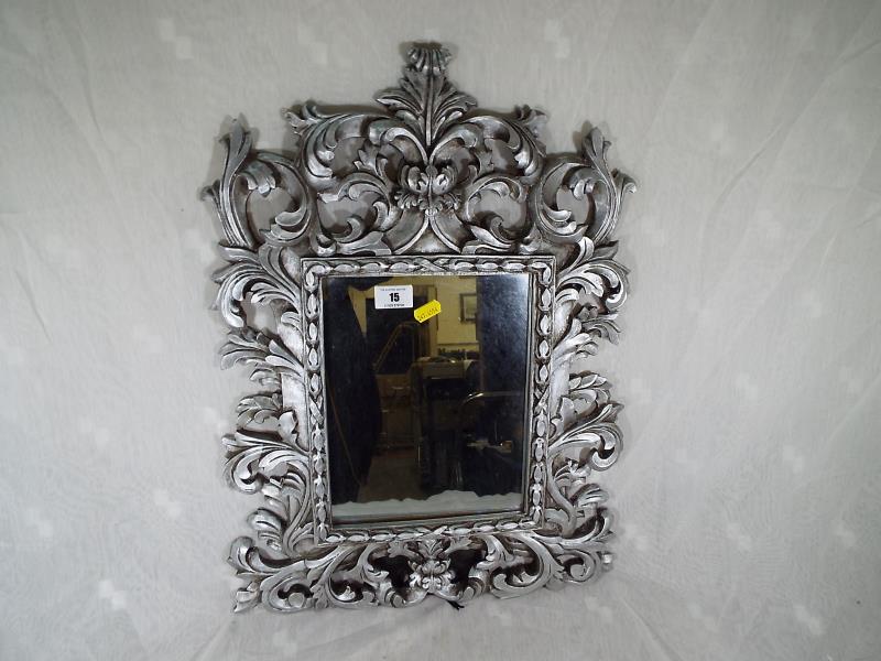 A heavy good quality mirror with scrolling decoration, overall size 55 cm x 40 cm. Mirror size 25