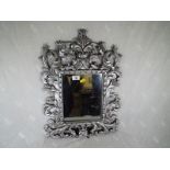 A heavy good quality mirror with scrolling decoration, overall size 55 cm x 40 cm. Mirror size 25