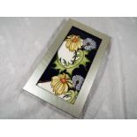 Moorcroft Pottery - A framed plaque decorated in a floral pattern, frame size 25cm x 14.5cm - Est