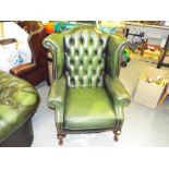 A green leather button back wing chair with cabriole supports