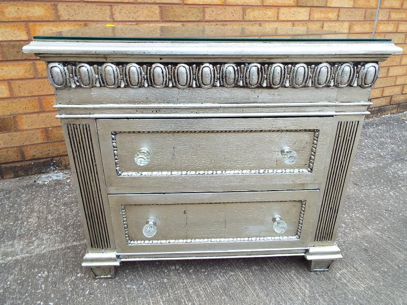 An ornate silvered bedside cabinet with twin drawers faceted glass handles and plate glass surface