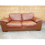 A two seater tan coloured leather settee approximately  90cm (h) x 190cm (w) x 90cm(d)