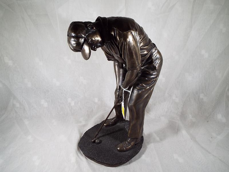 A bronzed figurine depicting a golfer, signed to the base,