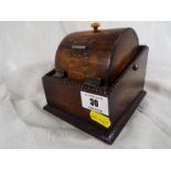 A novelty wooden cigarette dispenser in the shape of a revolving barrel,