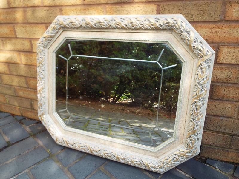 An octagonal bevel edged wall mirror with a carved foliate frame with gilded highlights,