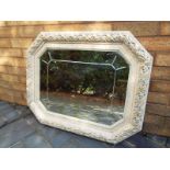 An octagonal bevel edged wall mirror with a carved foliate frame with gilded highlights,