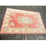 A 100% wool rug, pink with cream border and flowers,