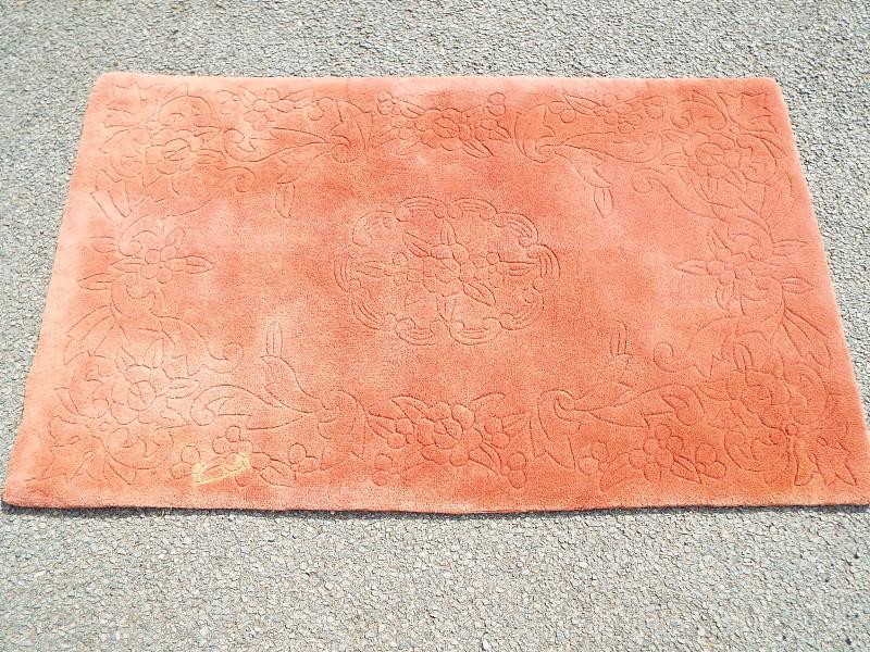 A rug, predominantly peach in colour,