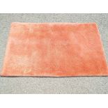 A rug, predominantly peach in colour,