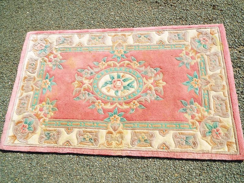 A 100% wool rug, pink centre with cream floral border,