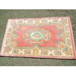 A 100% wool rug, pink centre with cream floral border,