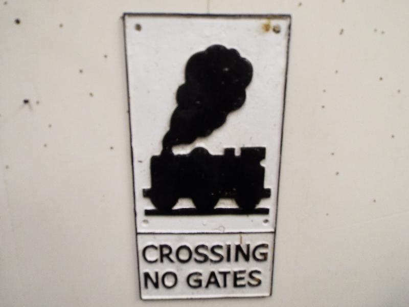 A cast iron sign with depiction of a locomotive, marked Crossing No Gates,