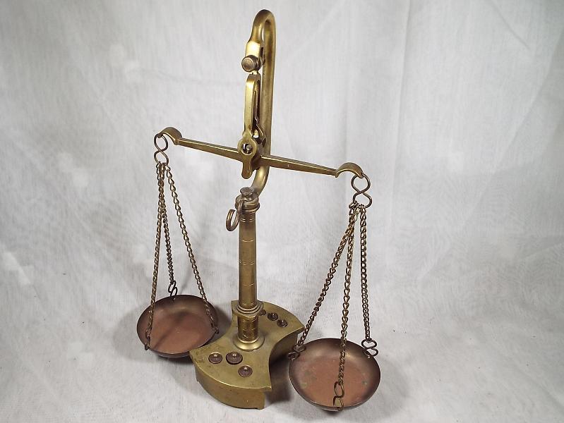 A brass weighing balance with graduated brass weights