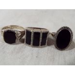 Two gentlemen's silver rings set with onyx and one further silver dress ring set with onyx and