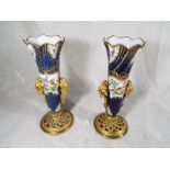 A pair of Royal Worcester reticulated bud vases decorated with depictions of birds on a cobalt blue