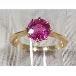 A lady's yellow metal ring set with central ruby coloured stone, possibly Continental,