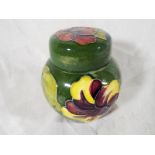 A Moorcroft Pottery lidded ginger jar decorated with hibiscus on a green ground,