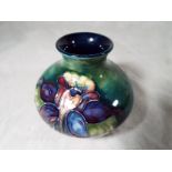 A Moorcroft Pottery squat vase decorated with columbine on a green ground,