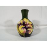 A Moorcroft Pottery small solifleur vase decorated with coral hibiscus on a green ground, 9.