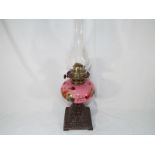 An oil lamp, the reservoir painted with roses on a pink ground,